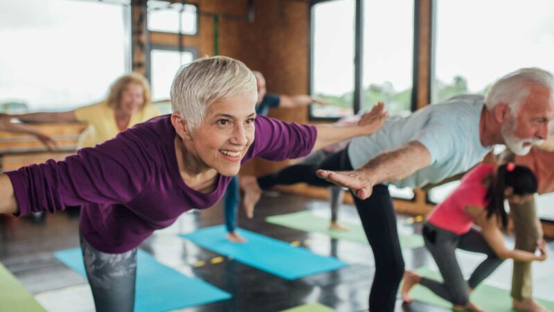 Older woman in group exercising - yoga balance